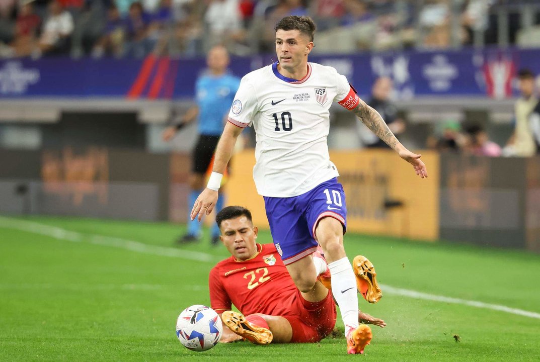 El capitán estadounidense, Christian Pulisic (d), fue registrado este domingo, 23 de junio, al disputar un balón con el centrocampista boliviano Héctor Cuellar (abajo), durante el primer partido del grupo C de la Copa América, en el estadio AT&T de Arlington (Texas, EE.UU.). EFE/Kevin Jairaj