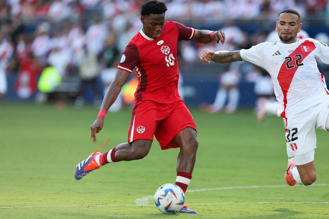 El delantero canadiense Jonathan David (i) dispara y anota al defensor peruano Alexander Callens (d). EFE/EPA/WILLIAM PURNELL